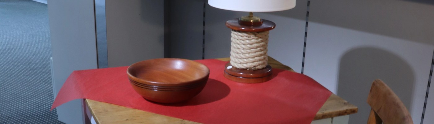 lampe "winch" et bol en bois exposés sur une petite table en bois patiné